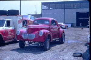 Red vintage car parked near garage.