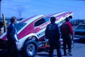 Drag car with open hood at event.
