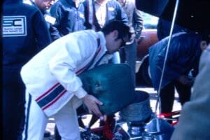 Man pouring liquid into race car engine.
