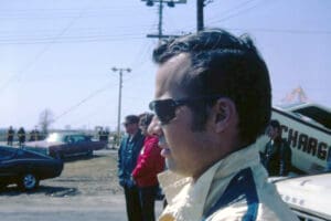 Man wearing sunglasses at outdoor car event.