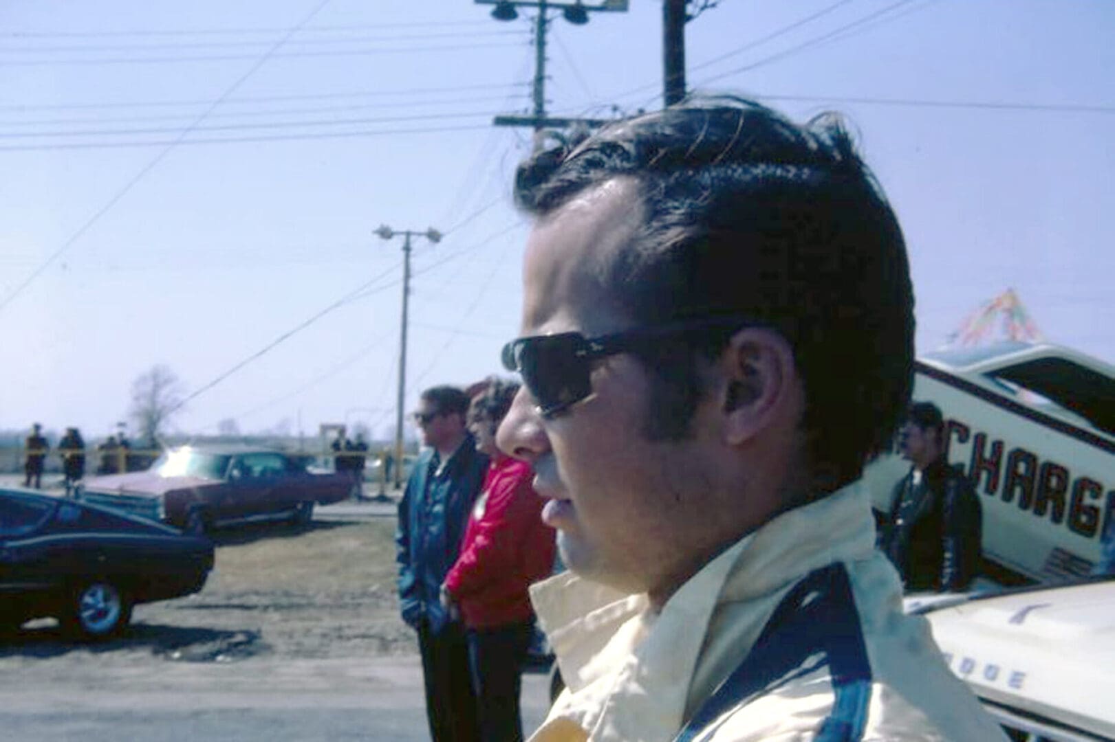 Man wearing sunglasses at outdoor car event.