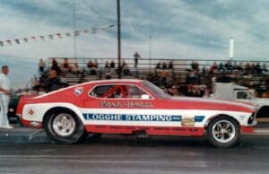 Red and white drag racing car on track.