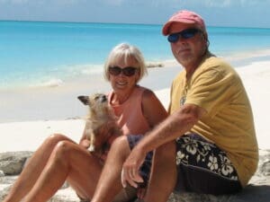 Couple with dog sitting on beach.