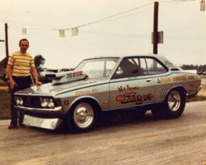 Man standing beside a vintage race car.