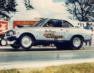 Vintage race car speeding on drag strip.
