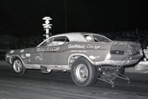 Drag racing car at night, launching rapidly.
