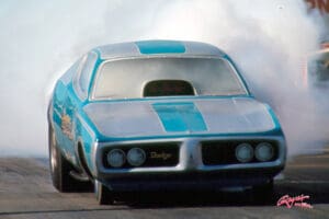 Blue race car emitting smoke on track.