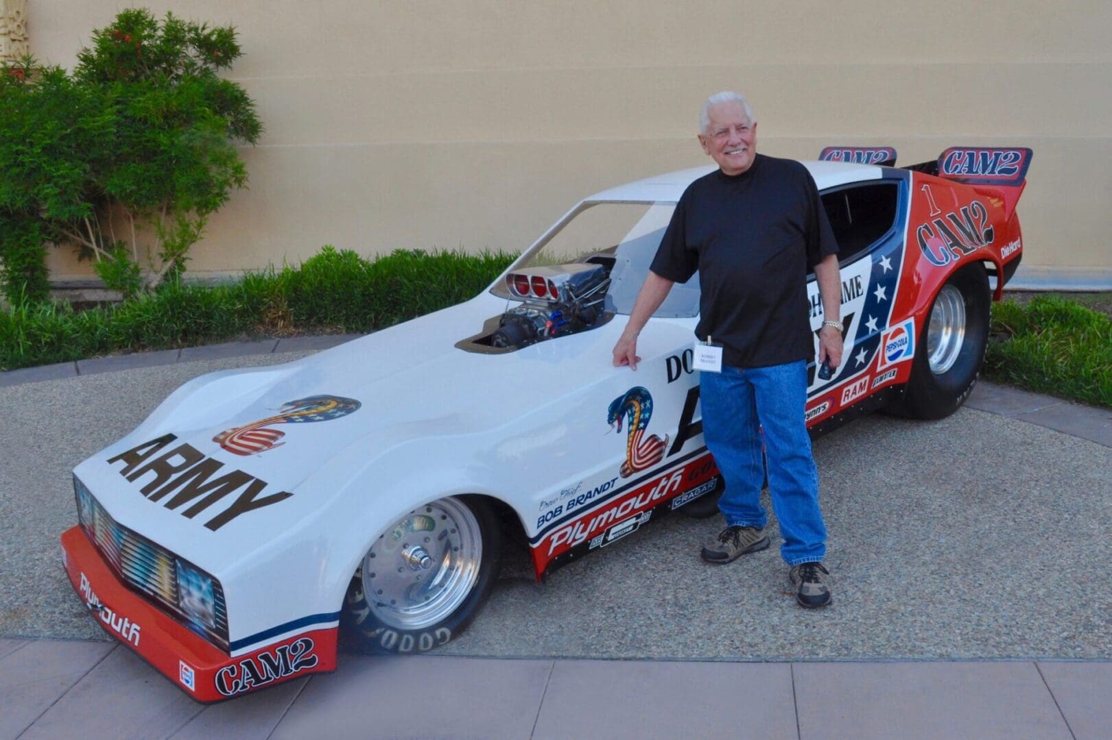 Man standing beside vintage drag racing car.