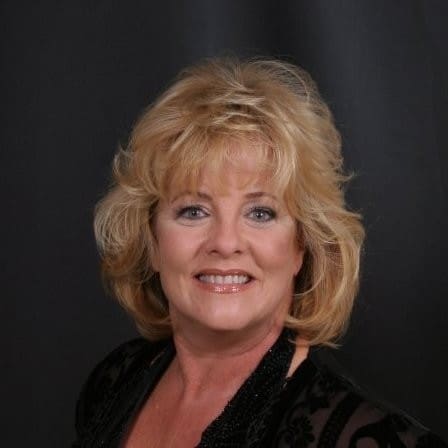 Smiling woman with blonde hair, black attire.