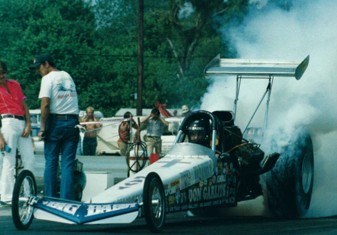A man engaging in drag racing as he drives a smoking drag car.