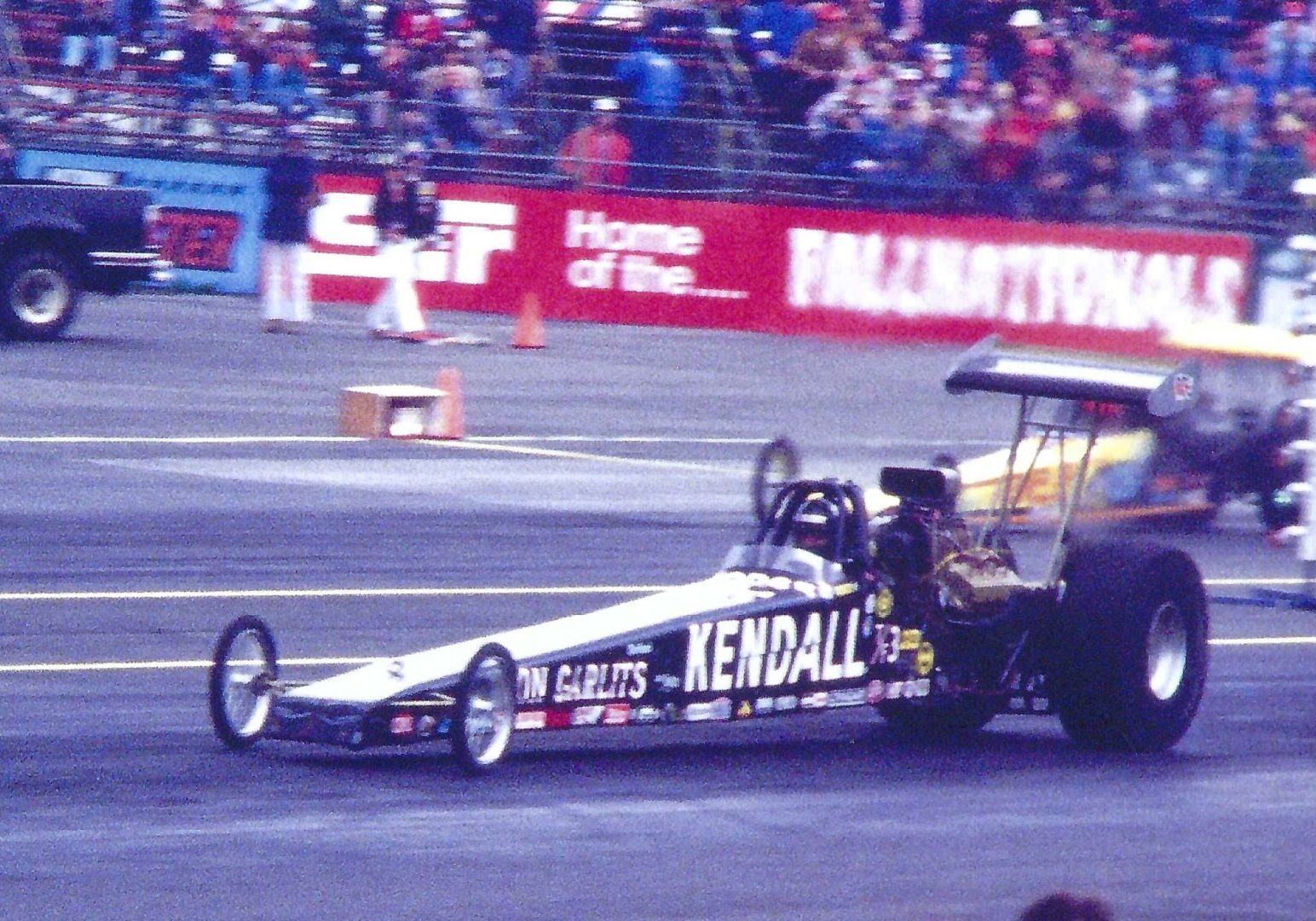 A man participating in drag racing, showcasing his skills and speed in front of a excited crowd.