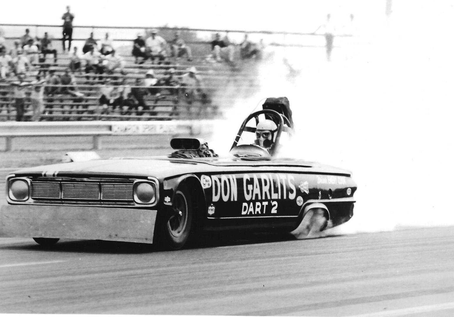 A black and white photo of a drag car with smoke billowing out, showcasing the thrilling world of Drag Racing.